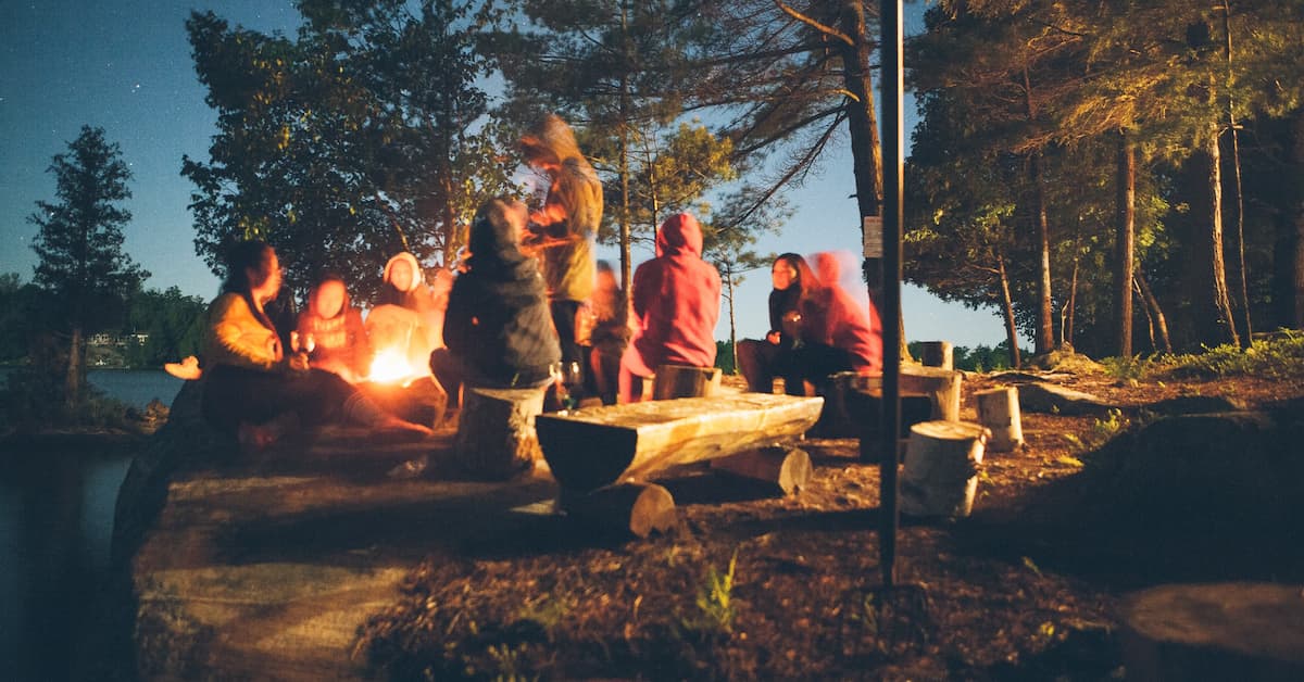 A group of friends sitting around bonfire in a jungle